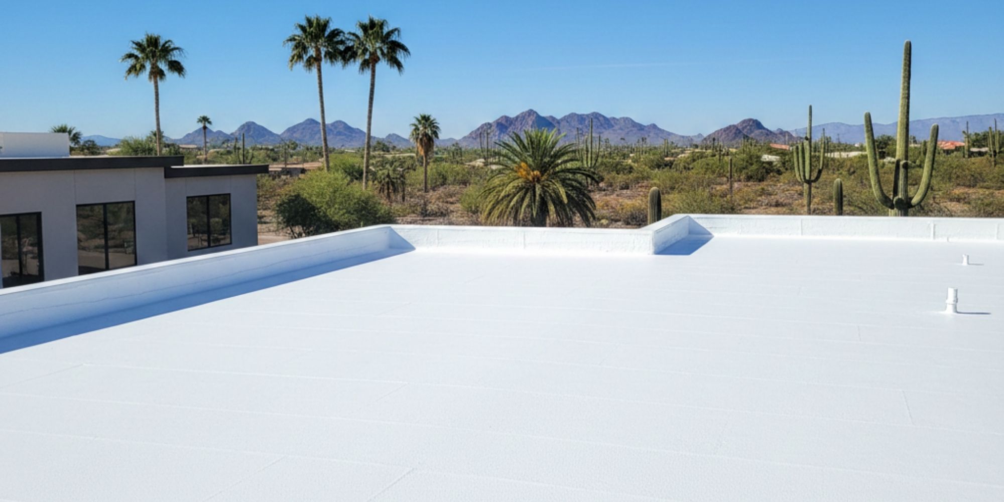 Professional installation of a seamless white spray foam roof on a Phoenix residential property under a clear blue sky.